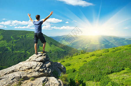 男人站在山顶上举起双手图片