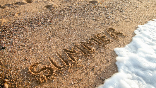 海浪在沙滩上湿写成的文字夏日上滚动的近距离图像旅游行和程的概念海浪在滩湿沙上写成的文字夏日上滚动的近距离照片旅游行和程的概念图片