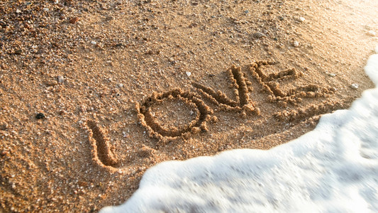 海洋浪擦除在湿沙上写下Love的字海洋浪擦除在湿沙上写下Love的字照片图片