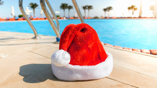 圣诞节新年和冬季假期的旅行和游概念夏季度假村中圣诞老人帽子在游泳池边的特辑照片圣诞节新年和冬季假日的旅行和游概念图片