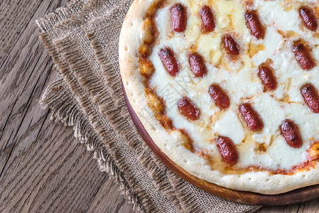 木制背景上配有马扎里拉和腊肠的比萨饼图片
