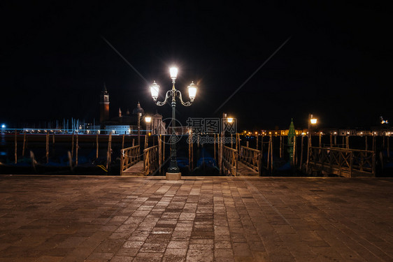 威尼斯运河和古老的建筑夜里歌多拉斯图片
