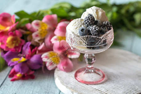 鲜花背景的香草冰淇淋里有冻浆果图片