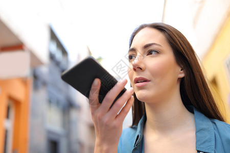 严重女孩在街上行走时使用智能电话语音识别应用程序图片