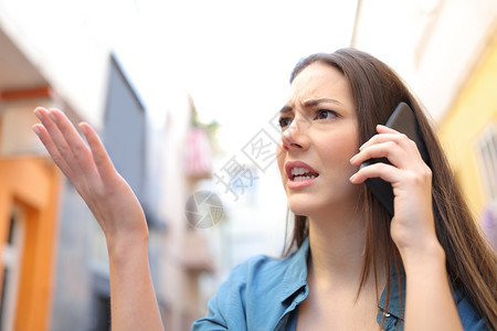 愤怒的女人用智能电话说抱怨在街上行走背景