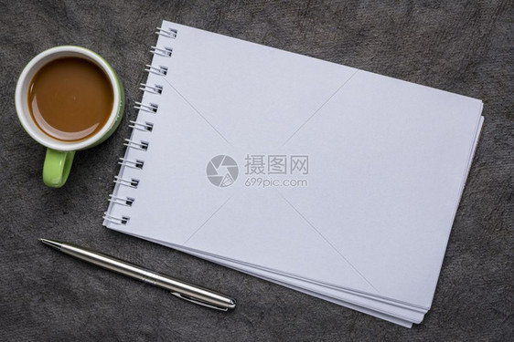 空白螺旋艺术素描本与配着咖啡的纸纹对图片