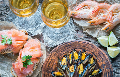 两杯白葡萄酒在木制桌上的海鲜图片