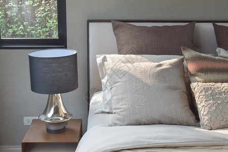 优雅风格的枕头设置在经典风格的床上用具和边桌的阅读灯图片