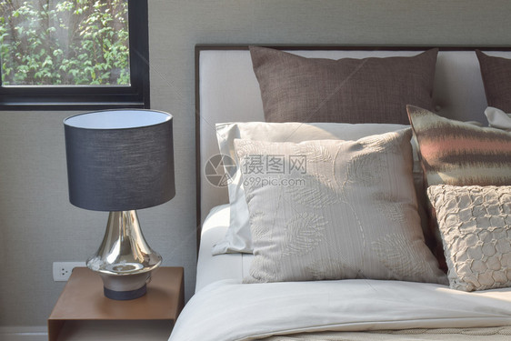 优雅风格的枕头设置在经典风格的床上用具和边桌的阅读灯图片