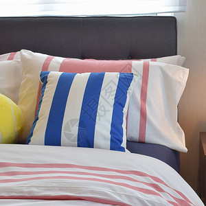 现代卧室内床上有彩色条纹枕头图片