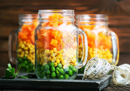 将蔬菜混合在玻璃罐和桌上的蔬菜图片