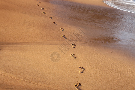 日落时热带海滩的浪和脚印背景图片