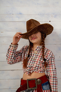 戴着宽的牛仔帽和穿着传统服装的小女孩摆姿势拍照背景图片