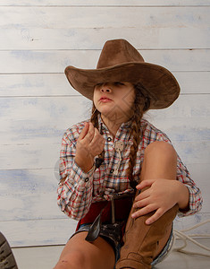 戴着宽的牛仔帽和穿着传统服装的小女孩摆姿势拍照图片