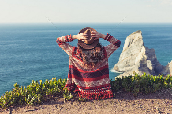 穿着旅行服和帽子坐着看蓝色的海洋和天空旅行概念照片穿旅行服和帽子坐着看蓝色的海洋和天空图片