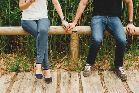 情侣在木栅栏上坐着牵手约会图片素材