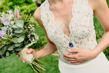 新娘用白裙子抱着她的婚礼花束图片