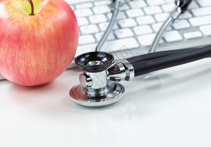医疗保健概念传统听诊镜和苹果背景有计算机键盘图片