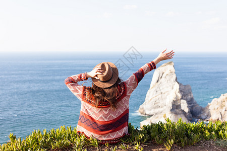 穿着旅行服和帽子坐着看蓝色的海洋和天空旅行概念照片穿旅行服和帽子坐着看蓝色的海洋和天空图片