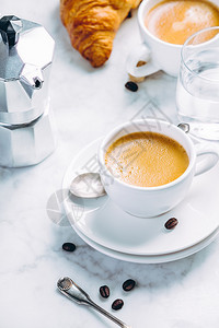 白大理石背景上的咖啡成分含水和牛角面包的白色杯子中咖啡浓缩早餐概念白色大理石背景上的咖啡成分白色杯子中的咖啡浓缩图片