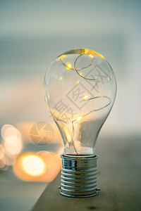 LED灯泡躺在木制桌子上是思想和创新的标志是模糊背景中的亮光图片