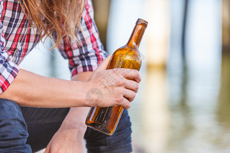 人在户外海滩上喝着酒瓶子;人和酗酒问题;人渣和酗酒问题;人渣和瓶子在海滩上喝着酒瓶子图片