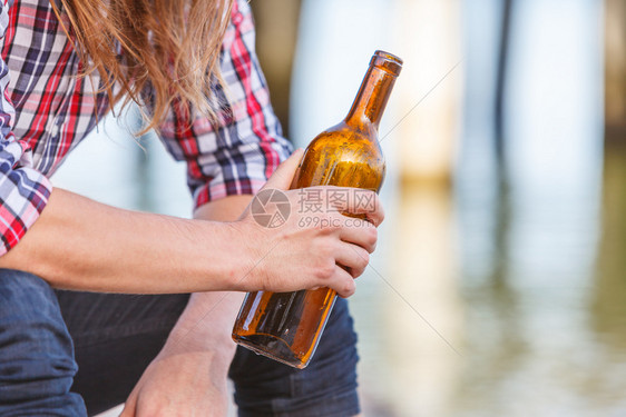 人在户外海滩上喝着酒瓶子;人和酗酒问题;人渣和酗酒问题;人渣和瓶子在海滩上喝着酒瓶子图片