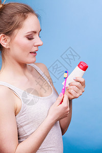 持牙刷和膏洗的妇女带着刷笑的姑娘快乐口腔卫生工作室拍蓝色背景图片