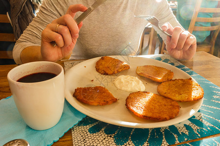 美味土豆煎饼和酸奶油杯茶传统菜女手握餐具美味土豆煎饼和酸奶油图片