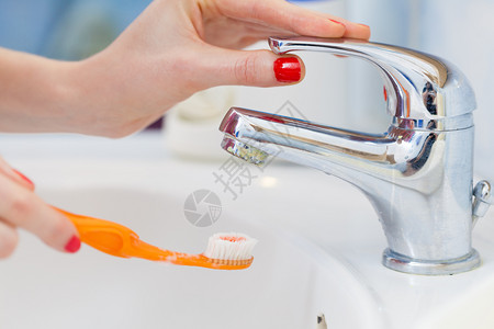 牙科口腔卫生浴室用具概念妇女将牙刷放在水下清洗牙刷妇女图片