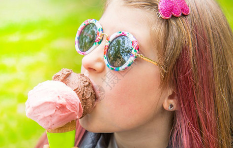 带着墨镜的笑小女孩在公园吃冰淇淋图片