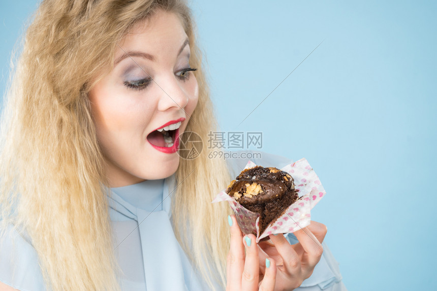 甜食糖让我们开心迷人的金发美女拿着味的巧克力蛋糕张开嘴想吃蛋糕蓝色的迷人女士拿着蛋糕图片
