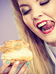 甜美的食物和快乐概念有趣是快乐金发女人拿着美味的巧克力蛋糕奶油兴奋的疯狂面容表情在紫罗兰上有趣的女人拿着奶油蛋糕图片