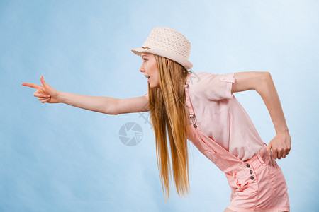 快乐的少女青年准备过暑假穿着粉红色服装戴太阳帽指着复制空间图片