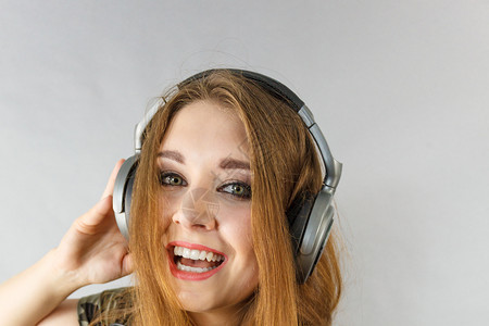 年轻女孩通过大耳机听音乐玩得很开心图片