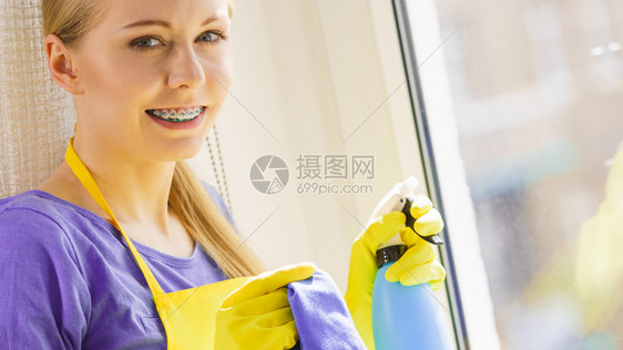 年轻家庭主妇在中用布和喷雾洗涤剂窗户清洁概念图片