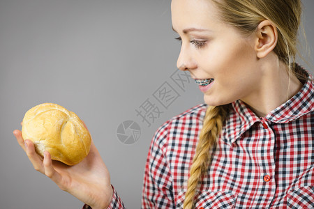 在灰色背景上拿着面包卷的快乐女人面包产品概念卷的女人图片