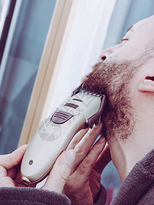 用电动剃须刀刮胡的有重点子男照顾面部头发戴困睡的眼罩剃胡子人图片