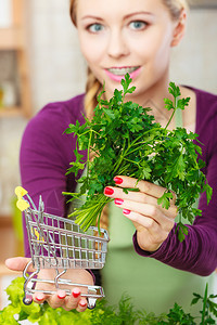 厨房里有很多绿色蔬菜的妇女拿着小型购物车厢里面有欧斯利图片