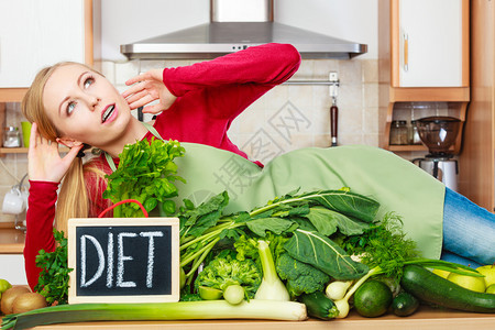 厨房的年轻女有很多绿色蔬菜在餐桌上配有饮食标志厨房的女有绿色食物蔬菜图片