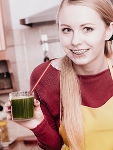 厨房的年轻女子拿着绿色健康的蔬菜果汁杯厨房的妇女拿着蔬菜汁图片