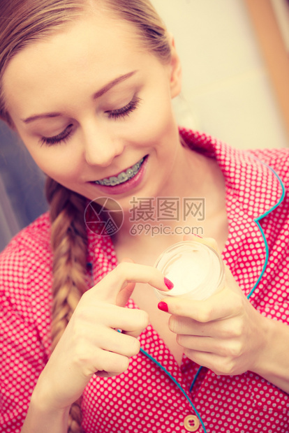 洗手间中年轻金发女郎在脸上施湿润的皮肤霜女孩照顾干皮肤层润湿剂护理治疗妇女施湿润的皮肤霜护理图片