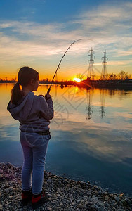 日落时在池塘中捕鱼的少女图片
