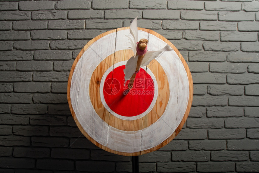一箭的木制粗目标在红圆的中心对着灰砖墙图片