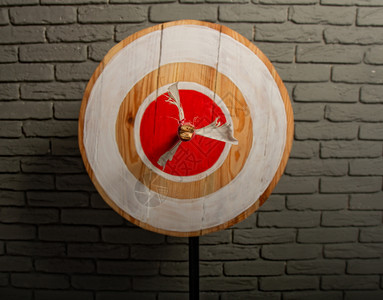 一箭的木制粗目标在红圆的中心对着灰砖墙图片