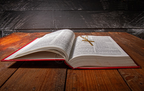 张开的圣经上面有红色的罩子还有一小块金属在旧的黑木质表面的铁链上图片
