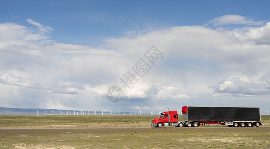 在犹他州公路上挂有货运集装箱的红色大卡车图片