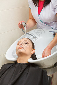 头发放松和型概念坐在黑斗篷上的妇女用理发师洗头女顾客头图片