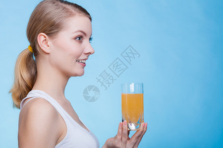 饮酒健康概念女人喝橙色口味饮料工作室拍的蓝底照女人喝的橙色口味饮料图片