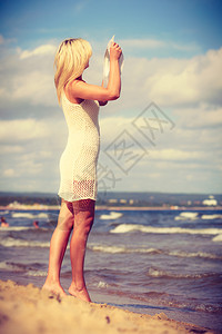 穿着浪漫服装的迷人金发女子在海滩散步和夏天放松图片